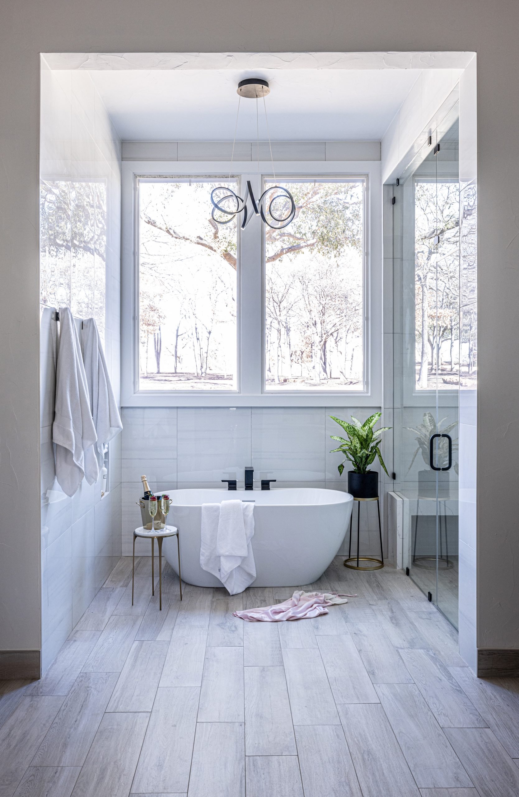 Basler_Bathroom renovation with stand-alone bathtub underneath eyecandy light fixture under bright window alongisde steam shower in Trophy Club Texas